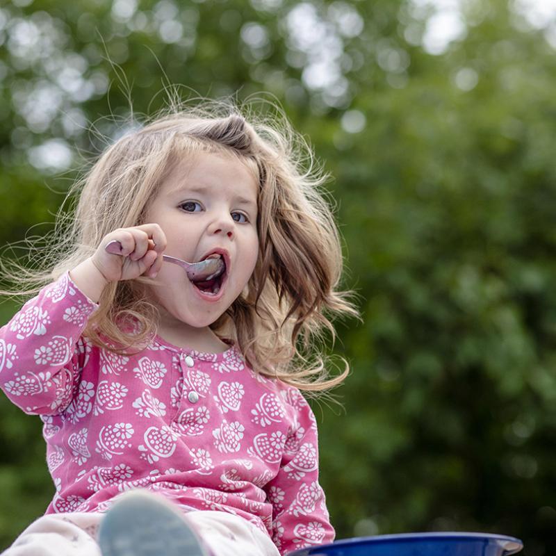 En liten flicka äter en parkmåltid sommaren 2021.